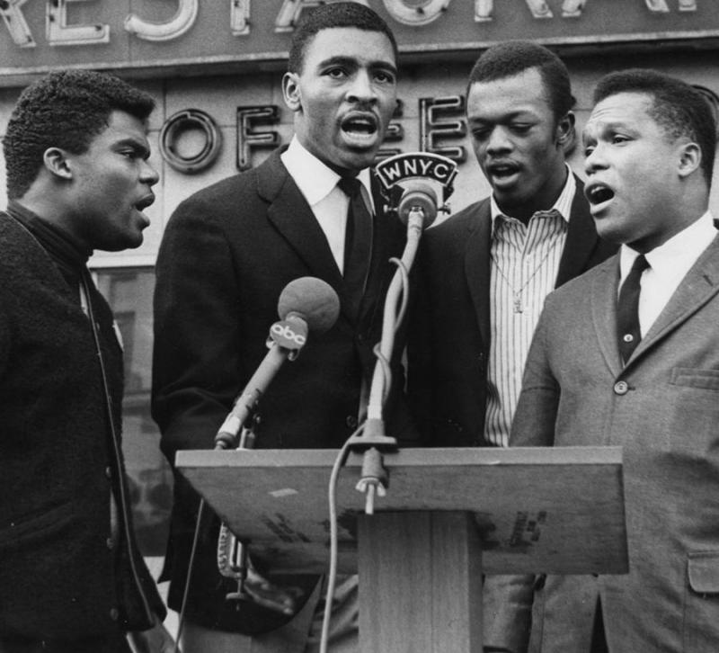 Four men singing at a microphone