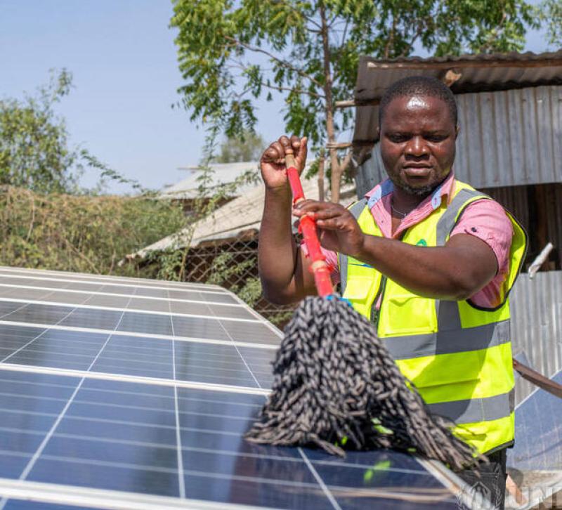 Man cleaning solar panels in a refugee camp