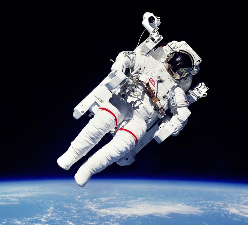 An astronaut in full space suit floating in space with the earth below