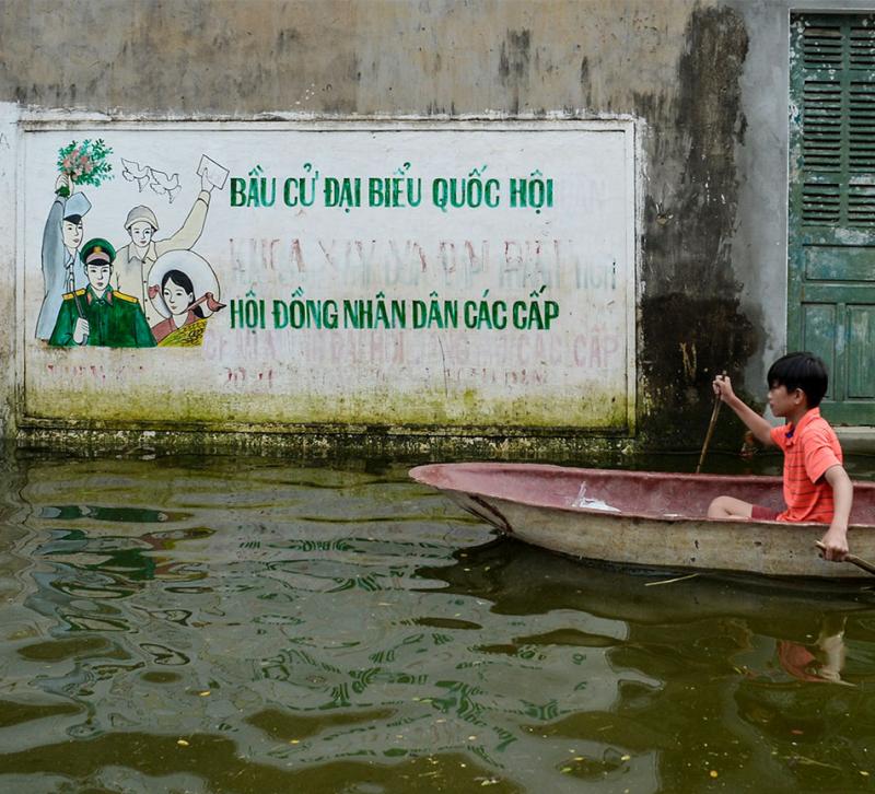 A small boy in a canoe on a flooded street