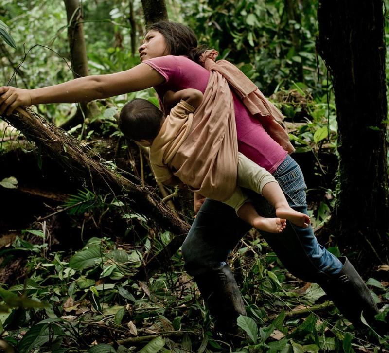 Woman with baby strapped to her chest clearing forest