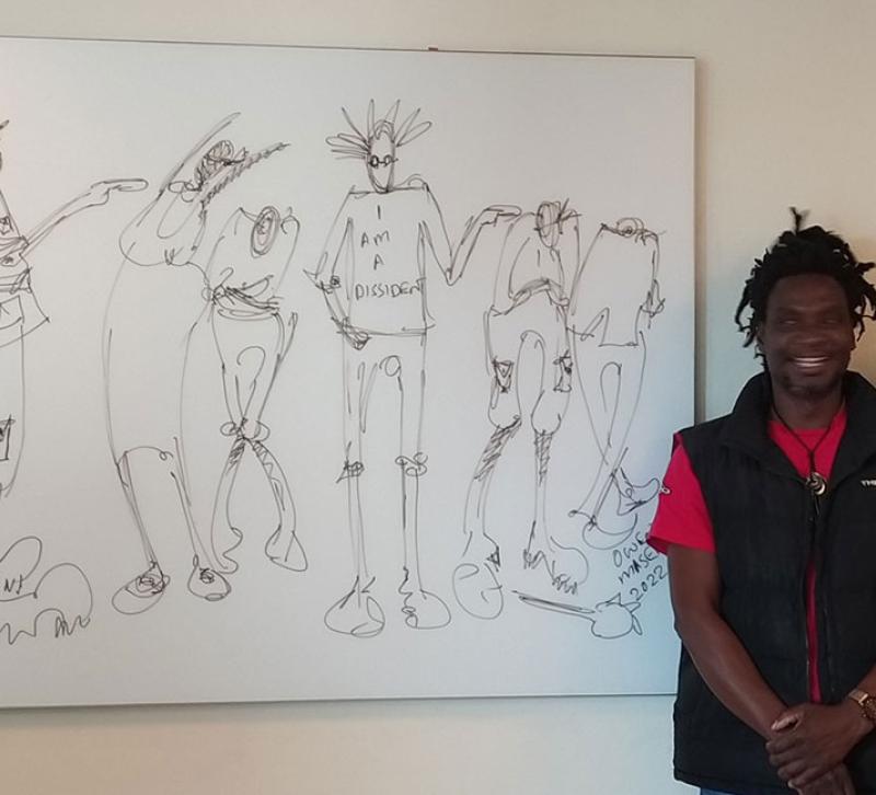 Two people stand alongside a black and white illustration on the wall