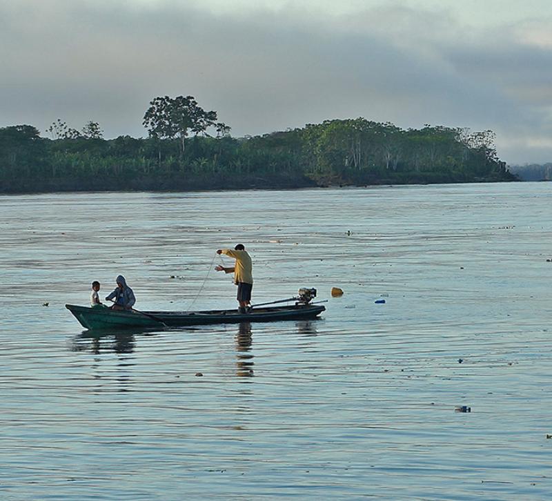 A fisherman in a boat reviews his nets on the Amazon river