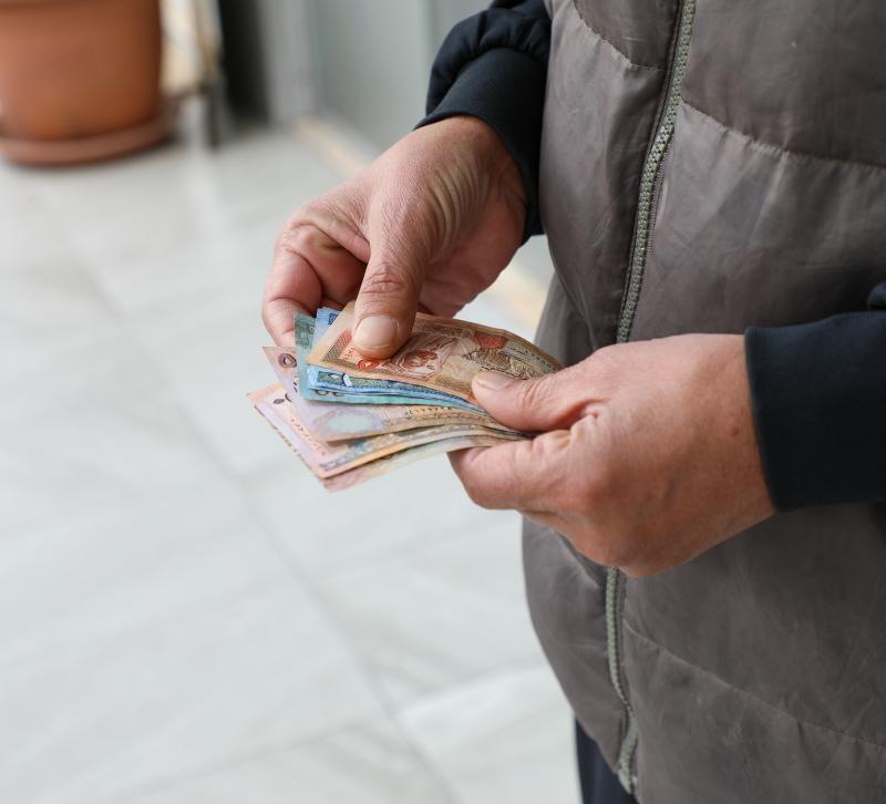 Close up of a Syrian refugee's hands as he counts his monthly cash assistance from UNHCR in Jordan