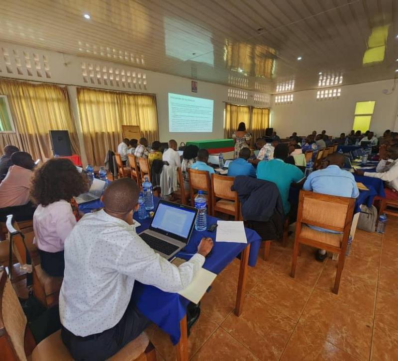 Rows of people seated, with laptops, viewed from behind