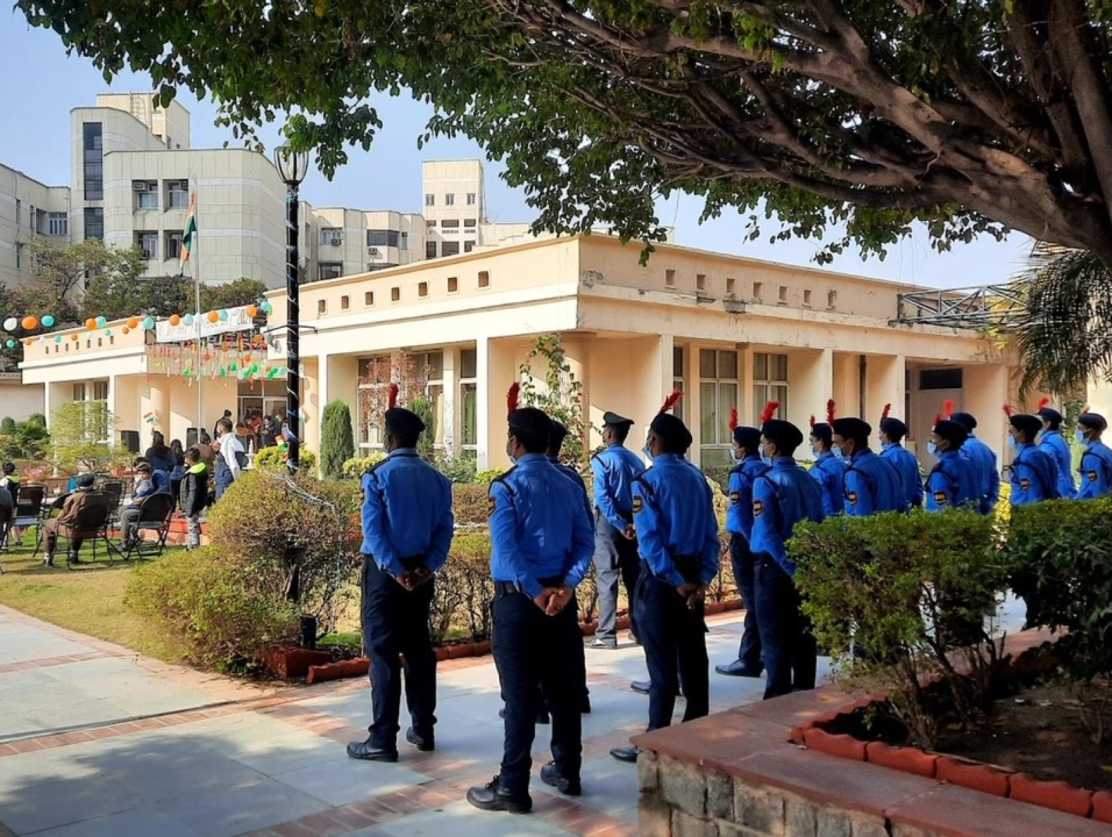 Indian security guards in bright blue uniforms lined up outside a public building