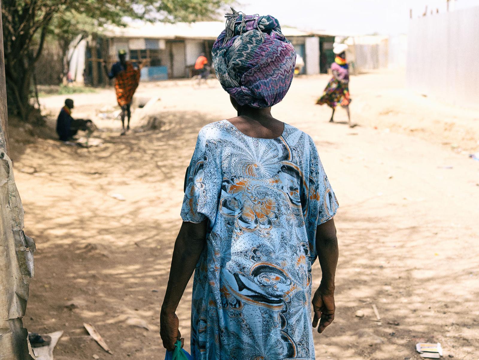 A woman in blue walking along a dusty road