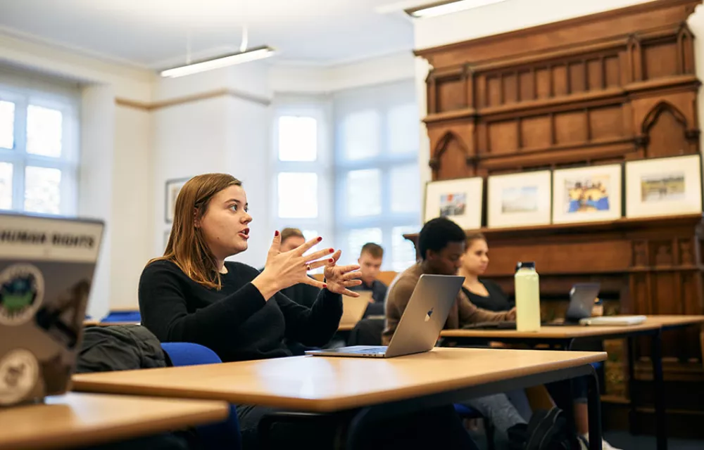 Student gesticulating while asking a question in classroom