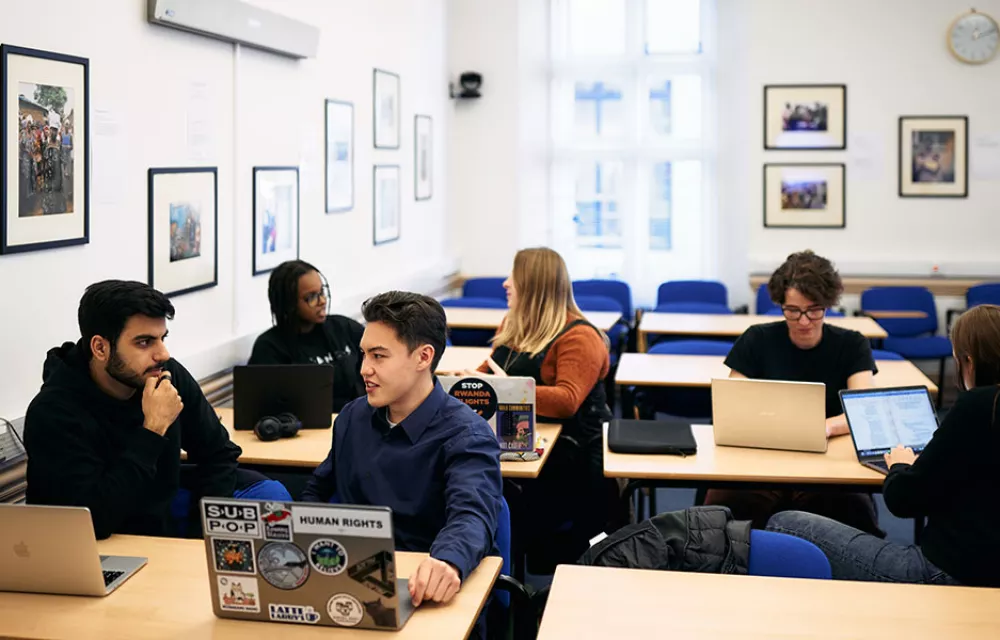 Five students sitting at desks in discussion