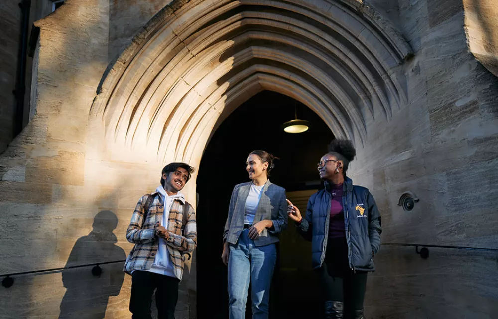 Three students emerging from arched doorway