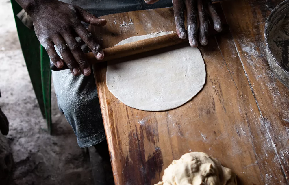 Hands rolling out a disc of dough