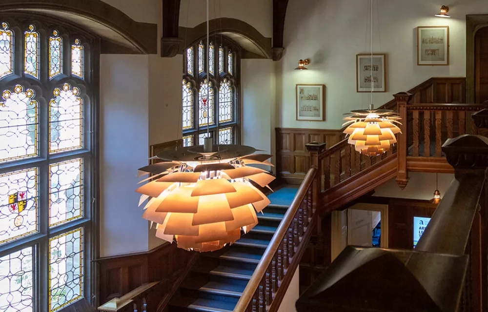A view down a staircase with artichoke lampshades and stained glass window