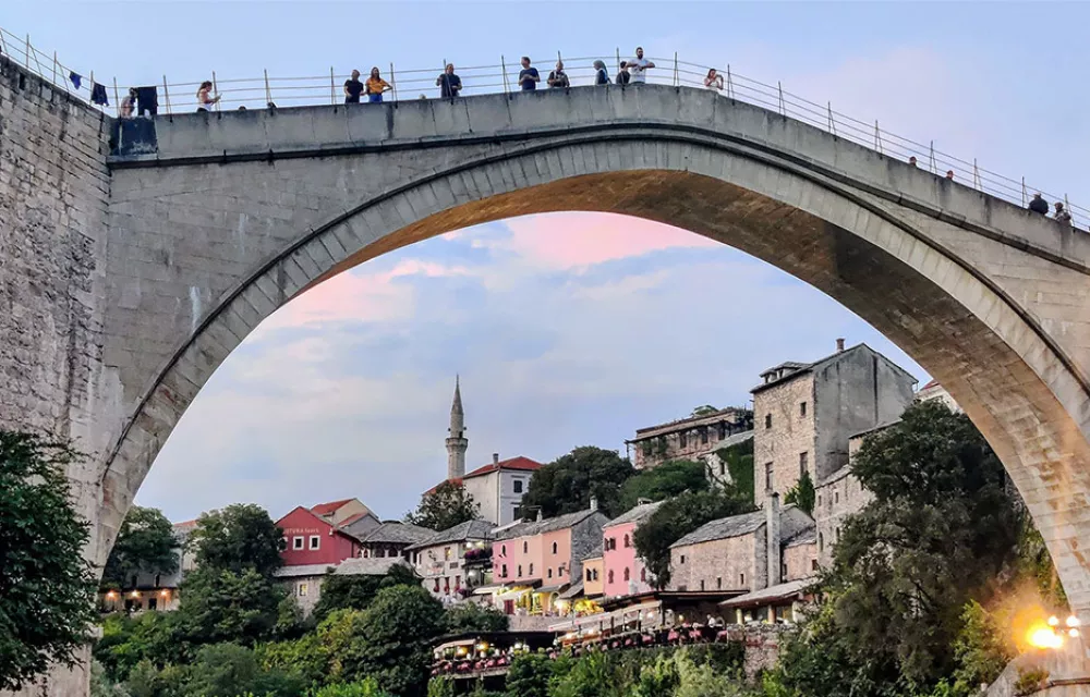 View through the arch of a bridge to houses and a minaret