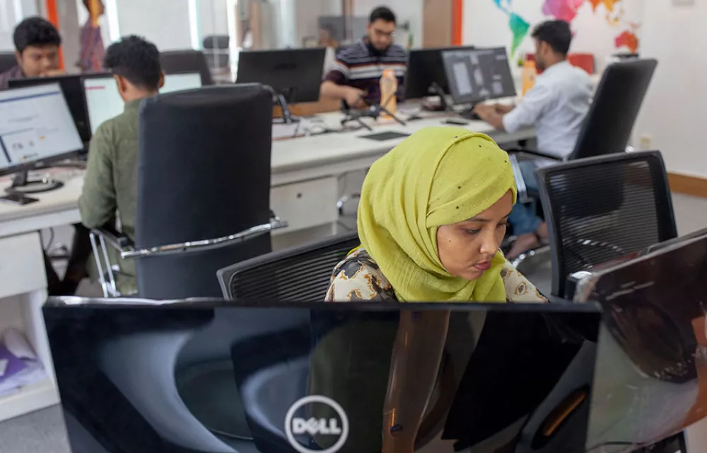 A woman in a yellow headscar sitting in front of a computer