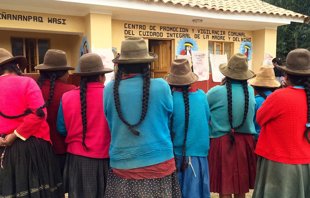A group of women wearing hats and colourful clothes viewed from behind