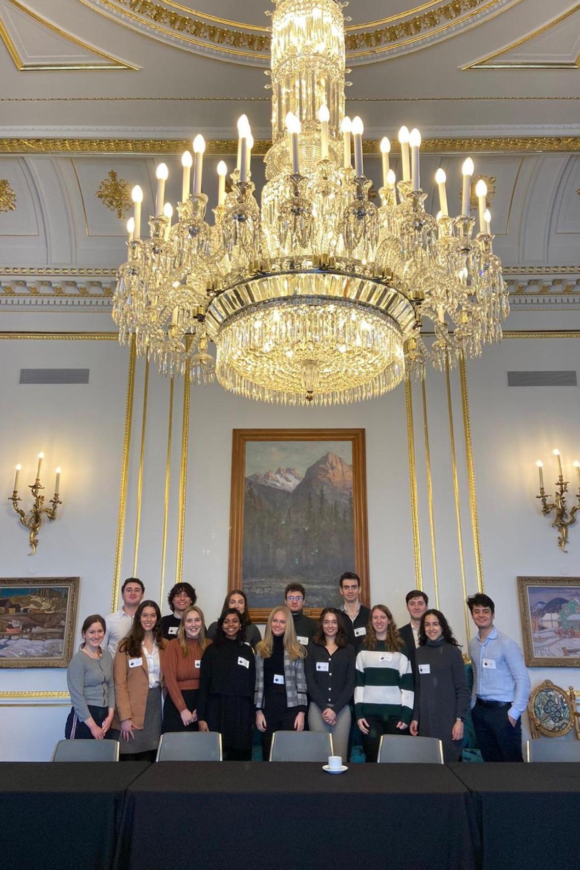 A group of students beneath a large ornate chandelier