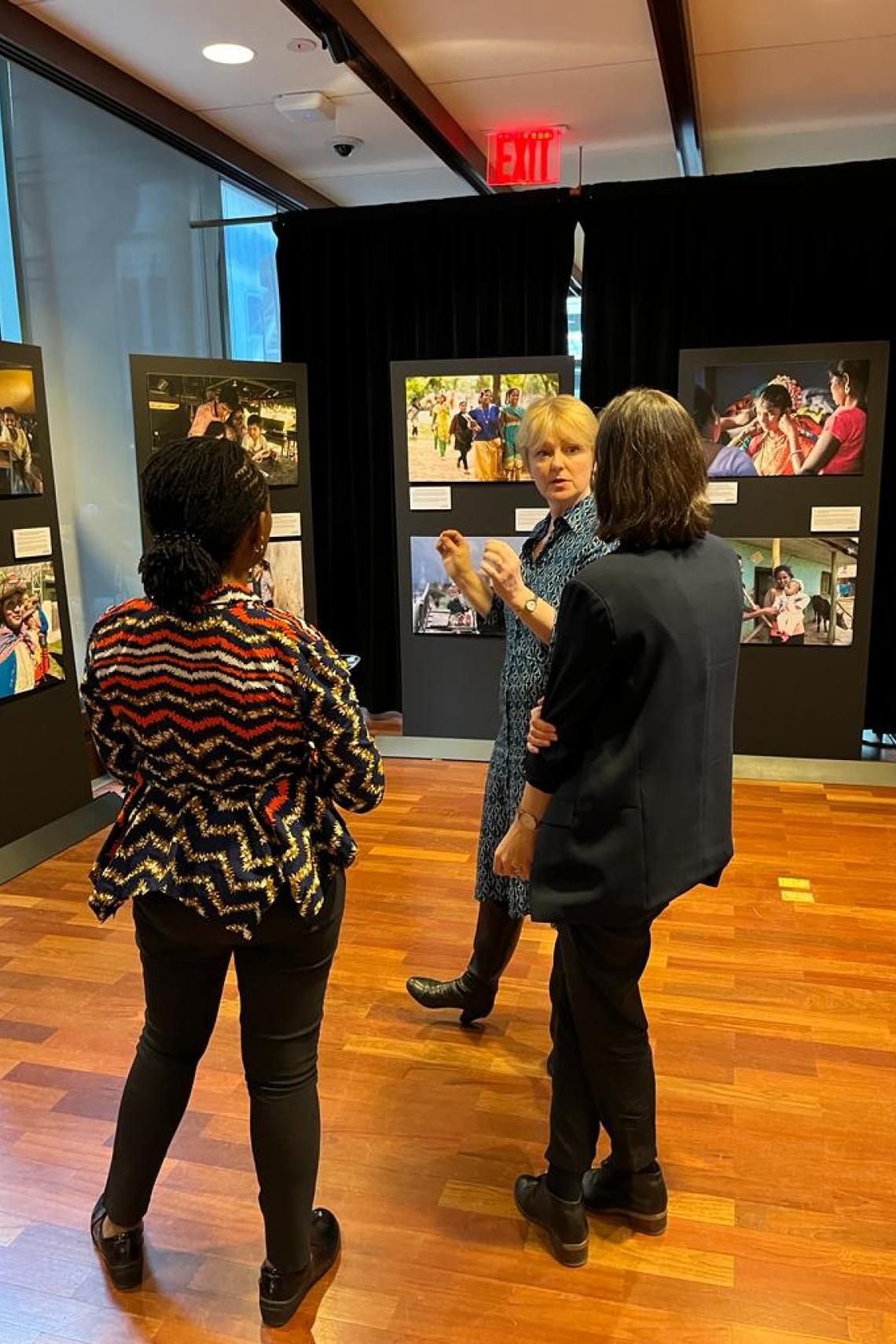 A group of people in conversation with photographs in the background