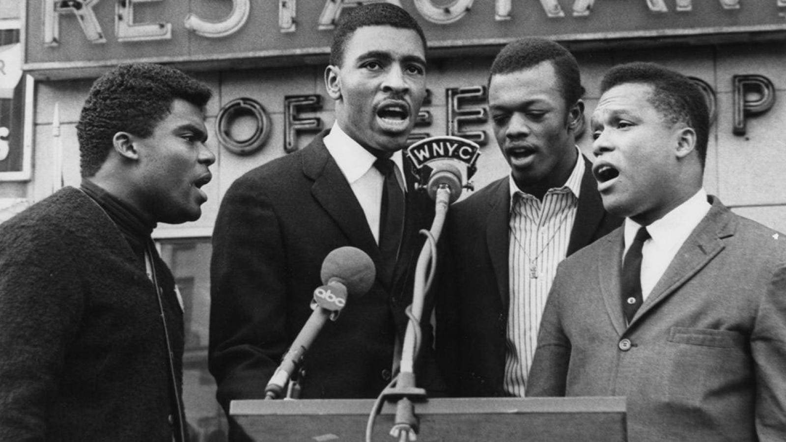 Four men singing at a microphone