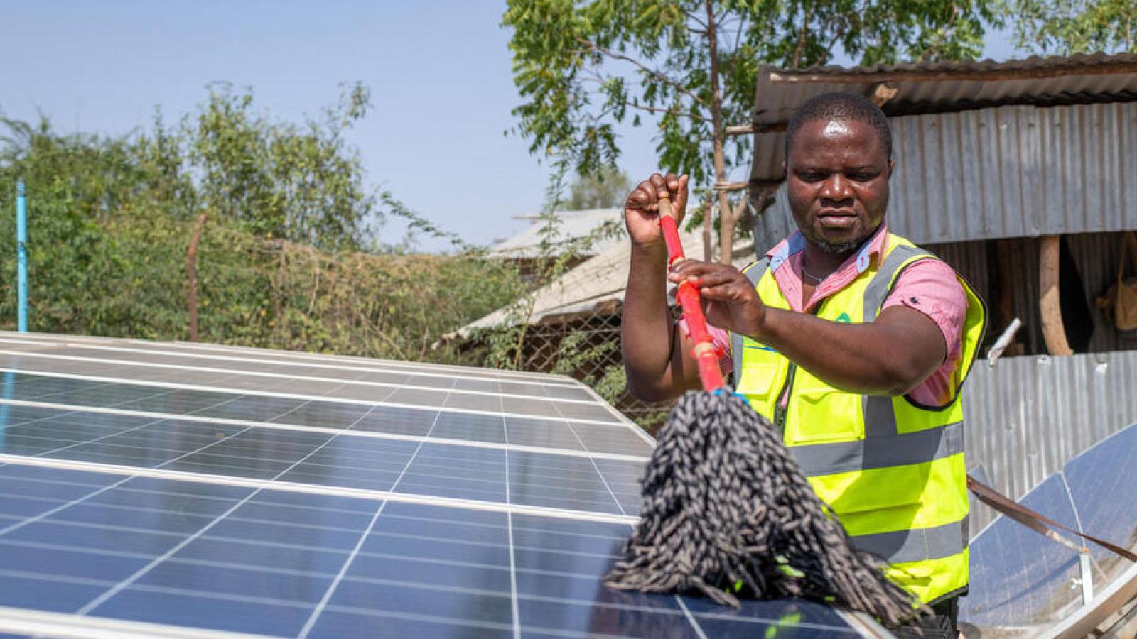 Man cleaning solar panels in a refugee camp