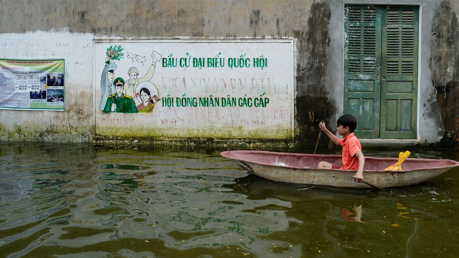 A small boy in a canoe on a flooded street