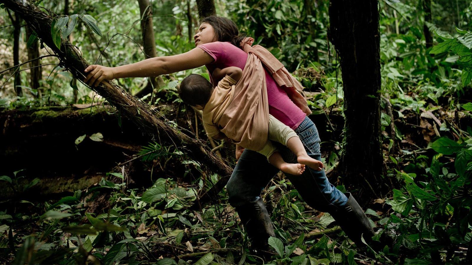 Woman with baby strapped to her chest clearing forest
