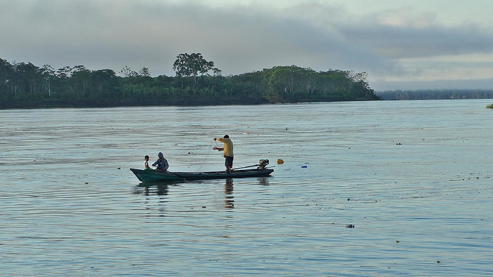 A fisherman in a boat reviews his nets on the Amazon river