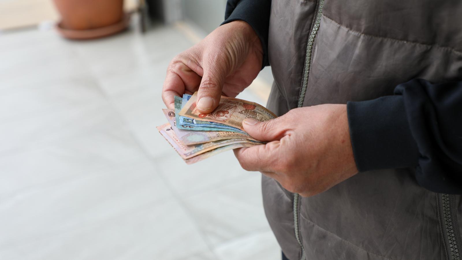 Close up of a Syrian refugee's hands as he counts his monthly cash assistance from UNHCR in Jordan