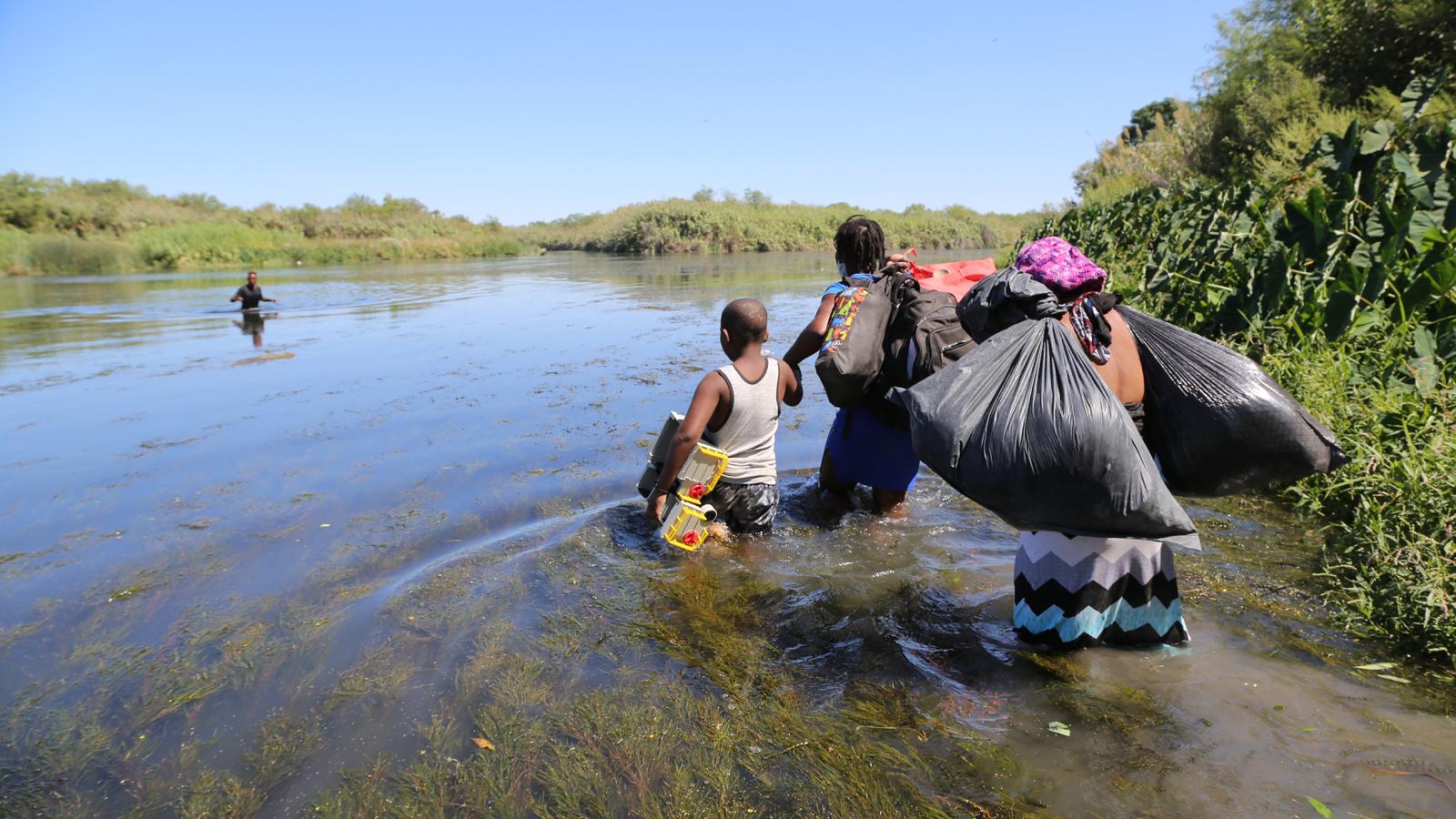A family starts to cross the Río Grande on foot carrying their possessions